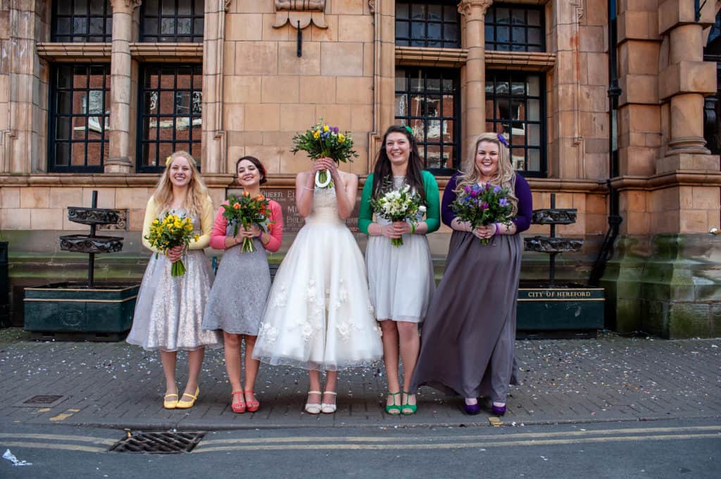 bride and colourful bridesmaids holding flowers